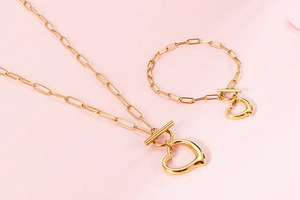 Detailed view of golden paperclip chain necklace and bracelet set with heart pendant