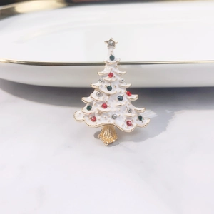 Close-up of white enamel Christmas tree brooch with colorful rhinestones and gold star