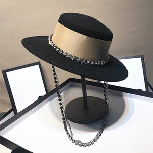 Vue détaillée du chapeau en feutre noir avec ruban doré et chaîne en strass brillant