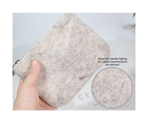 Close-up of handmade grey wool felt coin purse showing needle felt texture and zipper detail