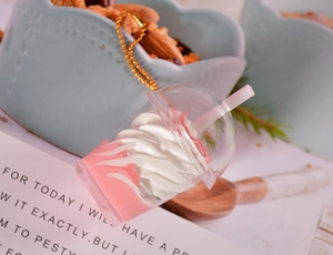 Détail d'un porte-clés mini milkshake rose et blanc avec chaîne dorée et paille déco