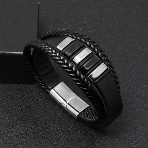 Macro shot of multi-layer braided leather bracelet with silver and black metal charms
