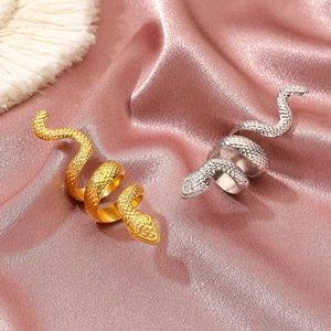 Punk snakeskin textured gold and silver coiled long rings on elegant pink satin fabric