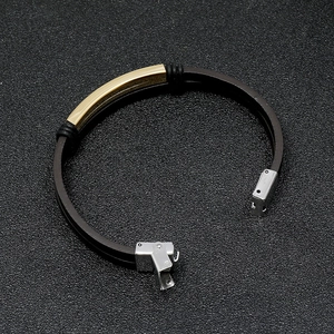 Detail of black leather bracelet featuring a gold curved metal plate and silver clasp