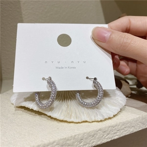 Macro shot of silver micro-pave cubic zirconia C-shaped hoop earrings on display card