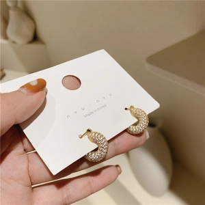Close-up of gold C-shaped hoop earrings featuring micro-pave cubic zirconia on a jewelry card