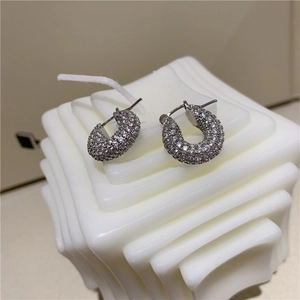 Detailed close-up of silver geometric hoop earrings with pavé micro-set cubic zirconia stones