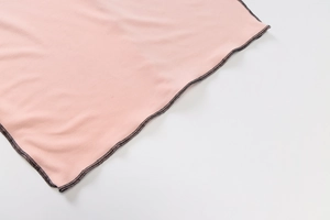 Detail shot of pink fabric with contrast black overlock stitching and soft texture