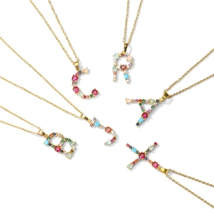 Macro view of alphabet letter pendants inlaid with colorful gemstones on gold chains