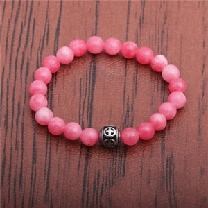 Macro view of pink beads and silver cross charm on a stainless steel beaded bracelet