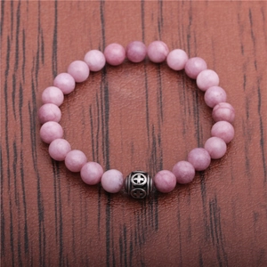 Detail of purple stone beads bracelet with a vintage silver cross charm on wood