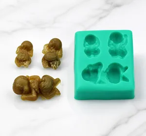 Detail showing a 4-cavity green silicone mold with finished 3D sleeping baby figures