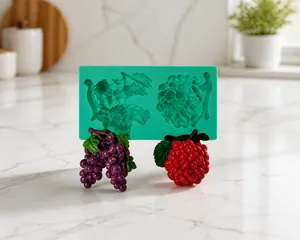 Detail view of green silicone mold with fruit-shaped grape and berry fondant decorations