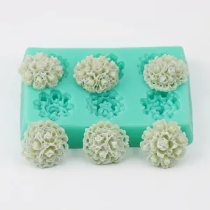 Detail of green 6-cavity flower silicone mold with white floral fondant decorations