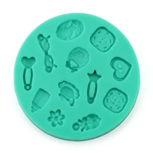 Close-up of mint green silicone fondant mold with baby themes like bottle and clothes