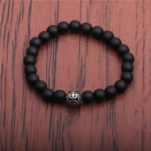 Detail of matte black stone bead bracelet featuring a silver cross engraved metal bead