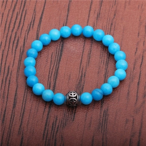 Detail of sky blue beaded bracelet with a vintage silver hollow cross charm on wood