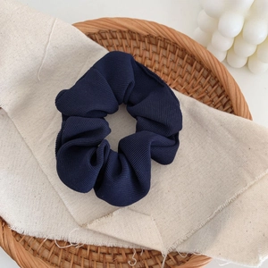 Detail showing ribbed fabric texture and navy blue pleats of the elastic scrunchie