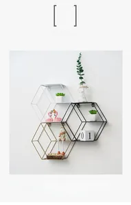 Close-up of three hexagonal iron wall shelves in gold, black, and white colors