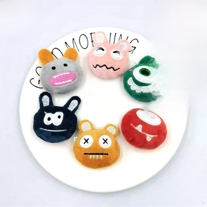 Détail de six broches monstres en peluche colorées sur une assiette en céramique blanche