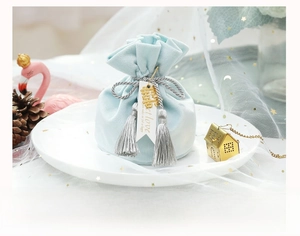 Detail of light blue velvet wedding favor bag with silver tassel and golden double joy charm
