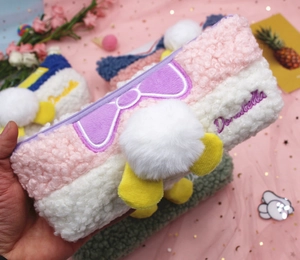 Detail of plush pencil case featuring lamb wool fabric with purple bow and soft pompom