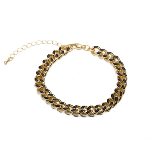 Detail of gold and black Cuban link bracelet with evil eye enamel and lobster clasp