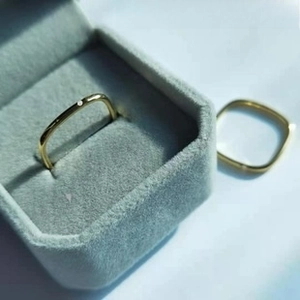 Detailansicht quadratischer Ringe aus vakuumvergoldetem Titanstahl auf blauem Samt