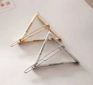 Close-up of minimalist gold and silver geometric triangle hair clips on soft background