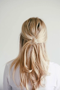 Minimalist metallic triangle hair clip styling on blonde hair for elegant half-up look