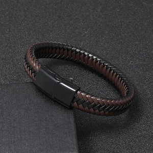 Dettaglio del bracciale in pelle intrecciata con chiusura magnetica nera su sfondo