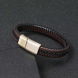 Dettaglio del bracciale in pelle intrecciata nera e marrone con chiusura magnetica dorata