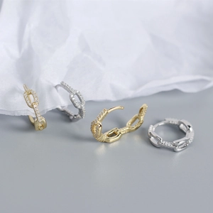 Close-up of gold and silver S925 sterling silver chain earrings with zircon on soft fabric