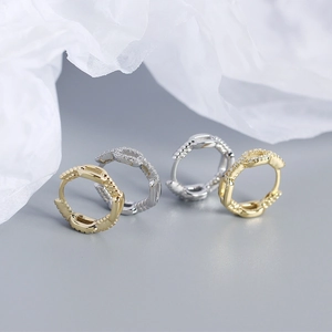 Macro view of gold and silver twisted chain huggie hoop earrings with sparkling zircon