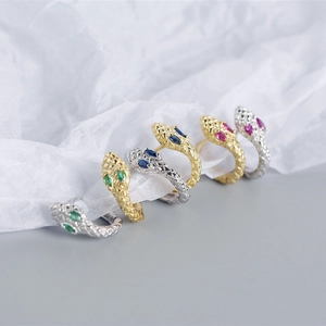Detailed view of snake-shaped rings in gold and silver with colored gemstone eyes