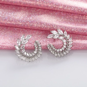 Detailed view of silver leaf earrings with full cubic zirconia on a reflective surface