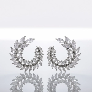 Detailed view of silver zircon earrings in elegant curved leaf design on white surface