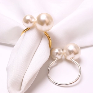 Close-up of gold and silver pearl napkin rings featuring elegant double pearl accents