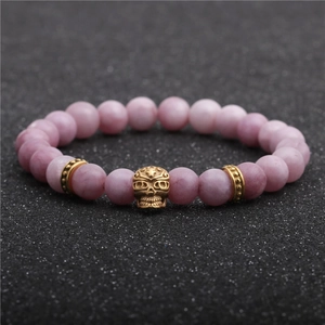 Detail of pink stone beads with gold skull charm on a masculine beaded bracelet