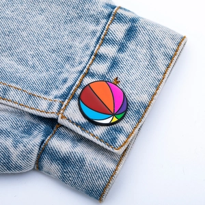 Détail d'une broche en émail géométrique colorée épinglée sur une manche en jean bleu