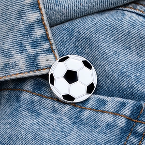 Détail d'une broche de football en émail noir et blanc épinglée sur un tissu en denim bleu