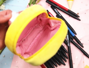Close-up of fluffy yellow plush pencil case with soft pink lining and durable metal zipper
