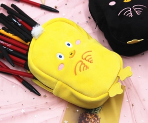 Detail of cute yellow and black plush chick pencil cases with embroidery and soft textures