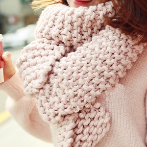 Close-up of thick light pink knitted scarf showing soft texture and warm chunky yarn weave