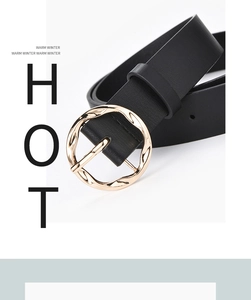 Close-up of a wide black belt featuring a unique textured golden wavy metal buckle