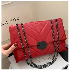 Close-up of red chevron quilted crossbody bag with stylish dark gunmetal chain strap