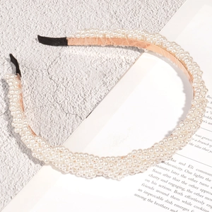 Eleganter Perlen-Haarreif mit roségoldenem Metallrahmen und weißen Perlen auf grauem Grund