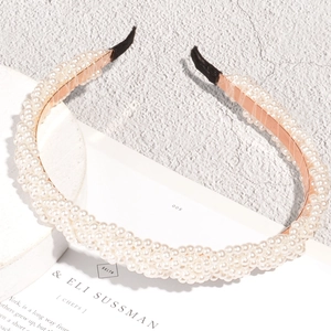 Eleganter mehrreihiger Perlenhaarreif mit Roségoldrahmen auf minimalistischem Steingrund