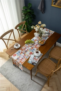 Detailed close-up of chenille table runner with colorful fish pattern and tassels
