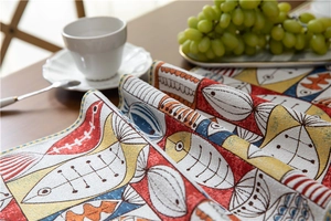 Close-up of woven chenille table runner featuring artistic red and blue fish patterns